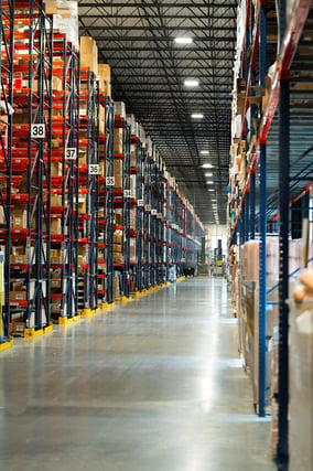 Long warehouse aisle between tall pallet racks with numbered rack locations