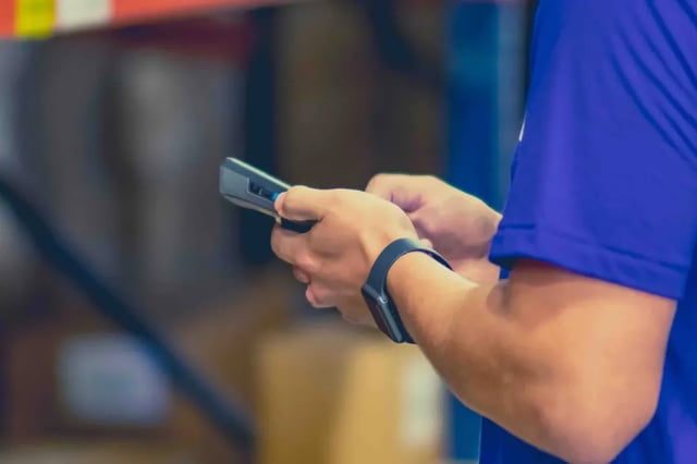 Warehouse associate holding a handheld barcode scanner in a rack aisle